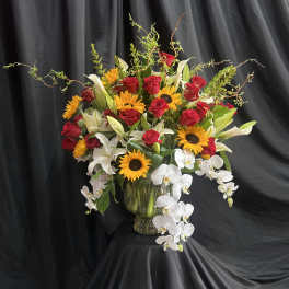 Mixed bouquet of red roses, white lilies, sunflowers, and white orchids in a glass vase
