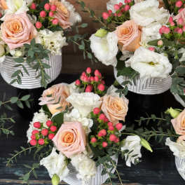 Pink roses and white blooms arranged in white ribbed containers