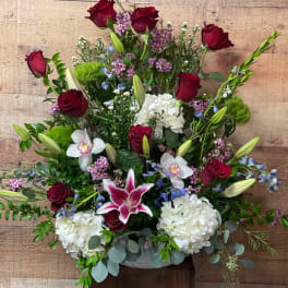 Mixed bouquet with red roses, white hydrangeas, and lilies in a low container