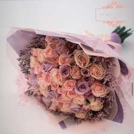 Bouquet of blush and lavender roses wrapped in pink paper