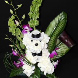 White teddy bear floral arrangement with purple orchids and green leaves