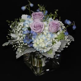 Lavender roses and blue hydrangeas in a clear glass vase