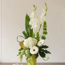 White floral arrangement in a lime green vase with gerbera daisies and tall blooms