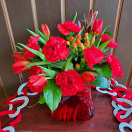 Red tulips and carnations in a red glass vase