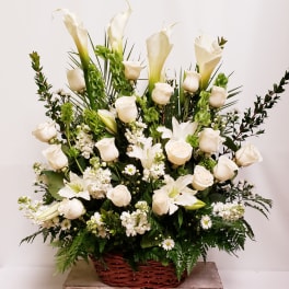 White roses and calla lilies in a wicker basket arrangement