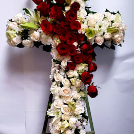 Cross-shaped floral arrangement with red and white roses on a stand