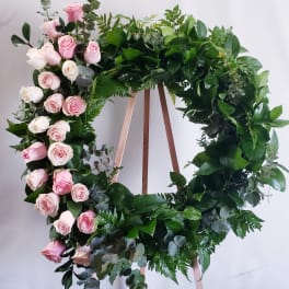 Circular wreath of pink and white roses on a wooden stand