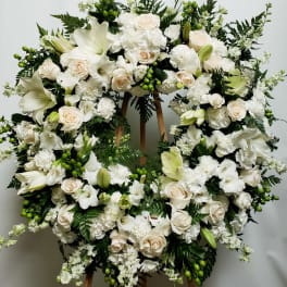 Large white floral wreath on a wooden stand