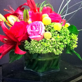 Bright pink and red floral arrangement in a glass vase