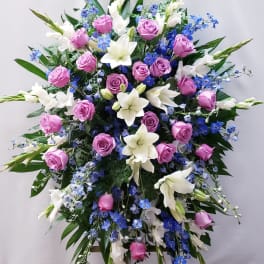Large standing spray of pink roses, white lilies, and blue flowers