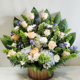 Arrangement of pale roses, white daisies, and purple flowers in a wooden basket