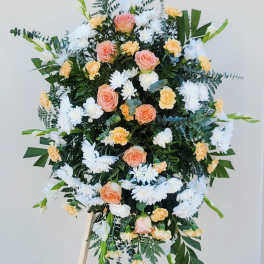 Standing floral spray with peach roses, white daisies, and yellow carnations