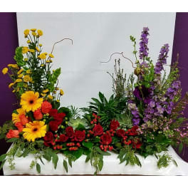 Large floral arrangement with red roses, yellow daisies, and purple spikes