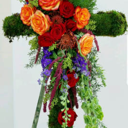 Cross-shaped floral arrangement with red and orange roses and purple flowers