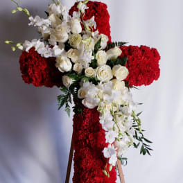 White roses and orchids arranged on a red floral cross