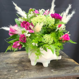 Pink and white floral arrangement in a white pig-shaped vase