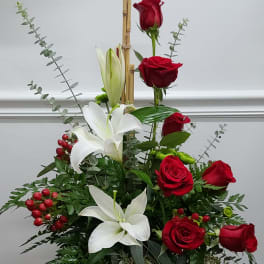 Red roses and white lilies in a tall arrangement with bamboo stakes