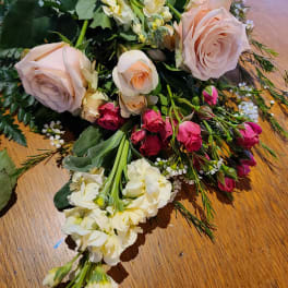 Bouquet of pale pink roses and cream flowers on a wooden surface