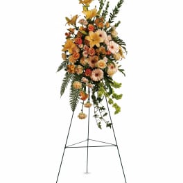 Tall floral standing spray with yellow lilies, peach roses, and gerbera daisies