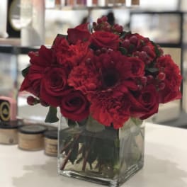 Red rose and carnation bouquet in a clear square vase