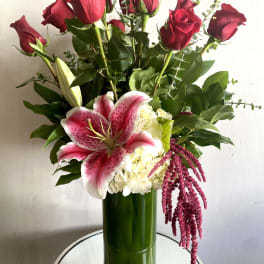 Bouquet of red roses and pink lilies in a tall green vase