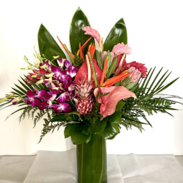 Tropical bouquet with pink orchids and anthurium in a green glass vase
