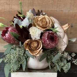 Floral arrangement in a white pumpkin-shaped vase with pink, white, and gold blooms
