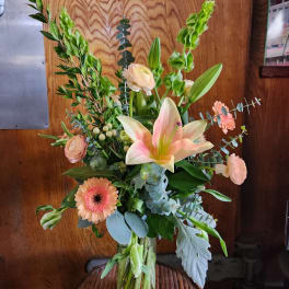 Mixed bouquet with a pink lily, peach gerbera daisy, and pale roses in a glass vase