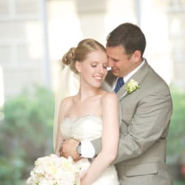 Bride holding a white and blush bouquet with groom behind her
