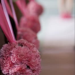 Pink carnation pomander with ribbon hanging indoors