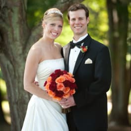 Bride and groom holding a bouquet of red and orange roses