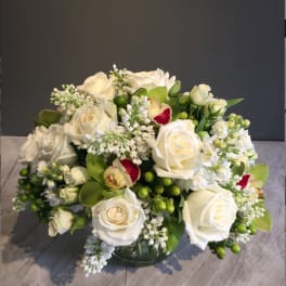 White roses and orchids arranged in a glass vase