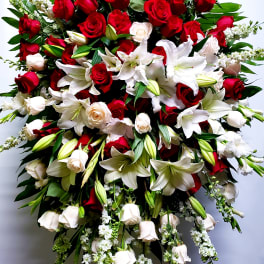 Large standing spray of red roses and white lilies with trailing white flowers