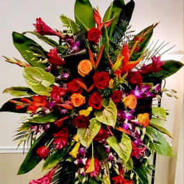 Large tropical floral arrangement with red and orange roses in a stand