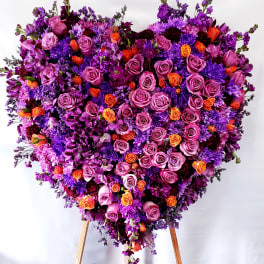 Large heart-shaped floral arrangement of purple, pink, and orange roses