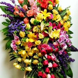 Large mixed floral standing spray with roses, lilies, orchids, and purple accents