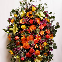 Large bouquet of orange and yellow roses with lilies and greenery