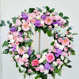 Heart-shaped floral wreath with pink, white, and purple flowers on an easel