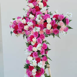 Cross-shaped floral arrangement of pink and white roses on a stand