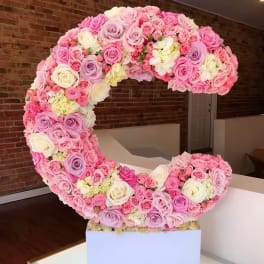 Large crescent-shaped arrangement of pink, lavender, and white roses