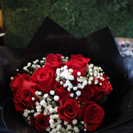 Bouquet of red roses with white baby's breath in black wrap