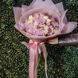 Pink rose bouquet wrapped in blush paper with a satin ribbon