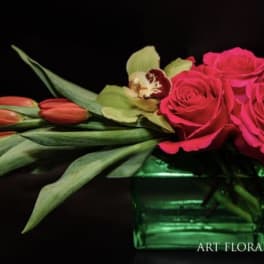 Pink roses and tulips arranged in a green glass vase