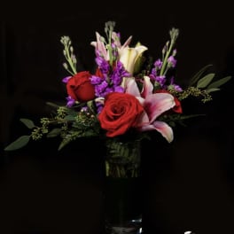 Red roses and pink lilies in a clear glass vase