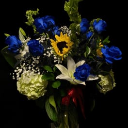 Blue roses and a sunflower in a glass vase