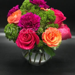 Bright pink and orange roses with purple carnations in a glass vase