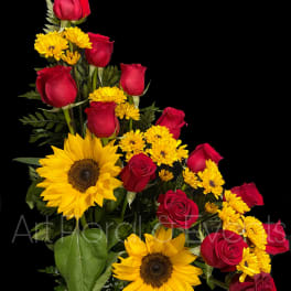 Red roses and yellow sunflowers in a white vase