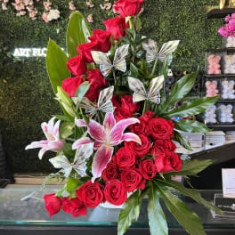 Red roses and pink lilies in a vase with folded money accents