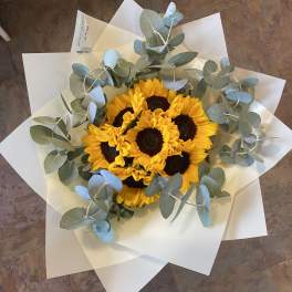 Bouquet of yellow sunflowers wrapped in white paper with eucalyptus