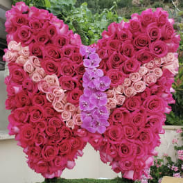 Heart-shaped rose arrangement with pink orchids in the center